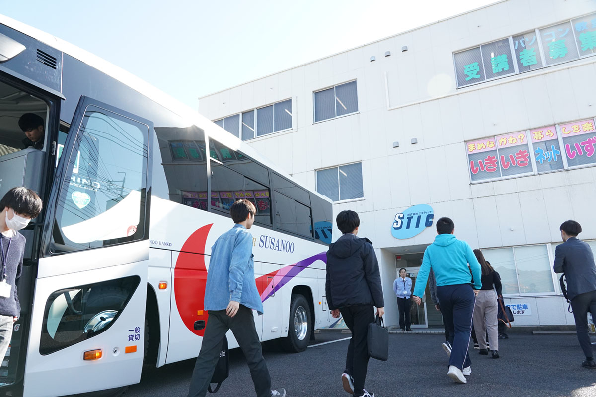 バスを降りて社屋に入る学生達